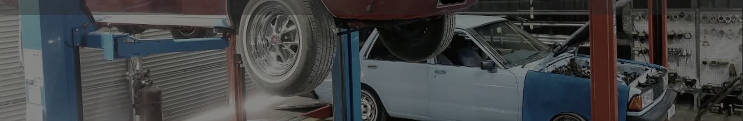 Inside the A2B Automotive workshop, with a classic car raised on the two post hoist and another alongside with the bonnet up